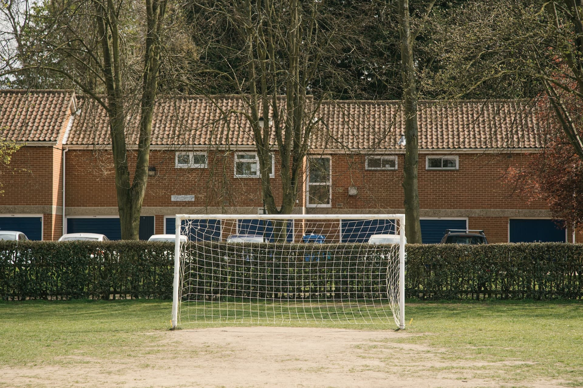 The clubhouse behind the hedge at the far side of the pitch