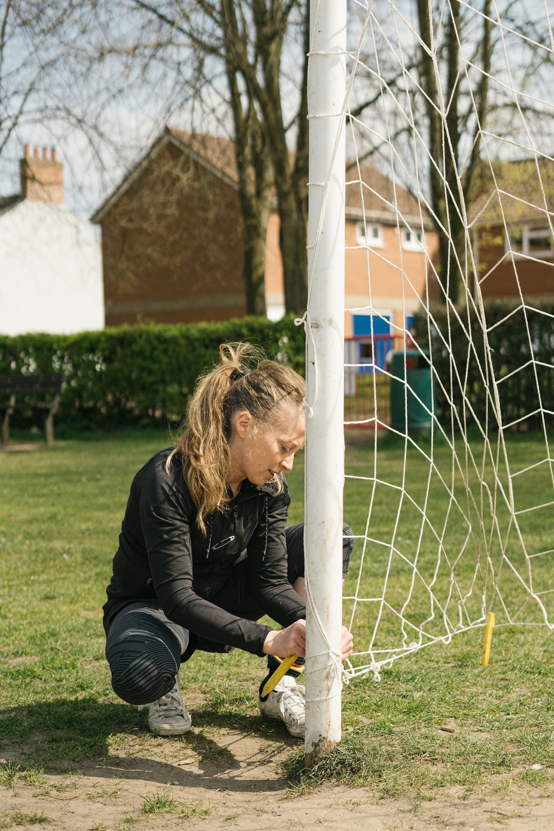 A player crouching to peg down the goal net before training
