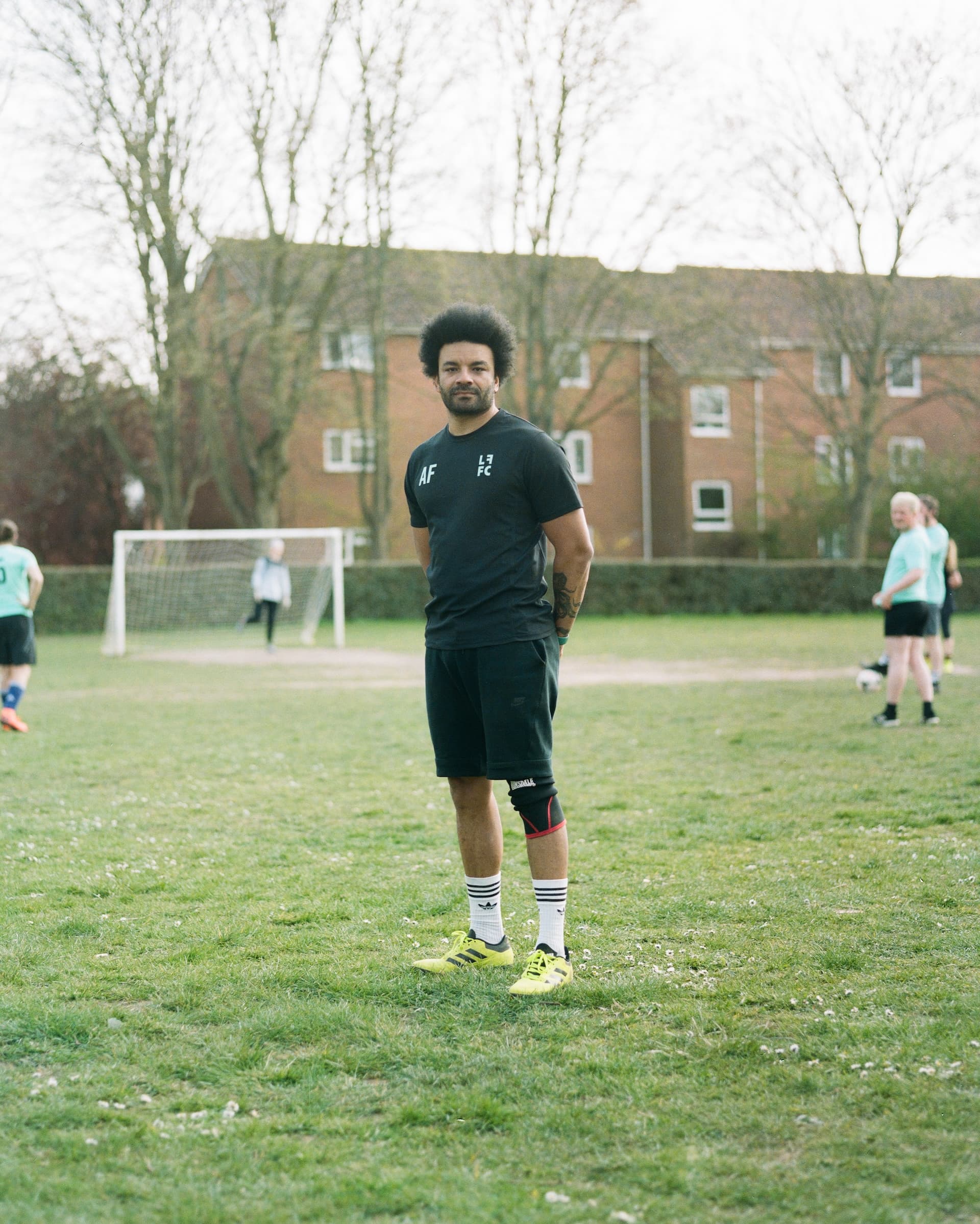 A player standing on the pitch in the black home kit